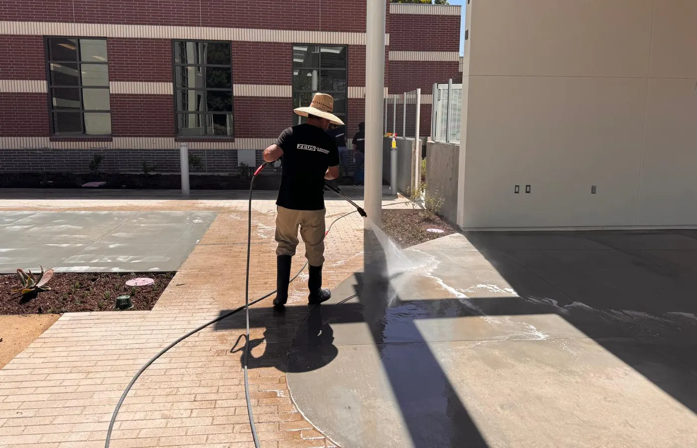 Zeus Cleaning Service crew member pressure washing a commercial building exterior in Buena Park, CA